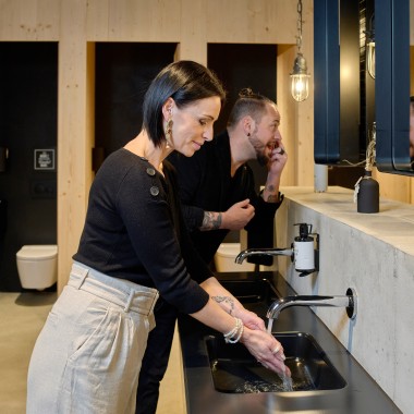 L'igiene e la pulizia sono una priorità assoluta nei bagni unisex delle aree comuni: con il rubinetto senza contatto Piave e il WCdoccetta AquaClean Sela. (© Geberit)