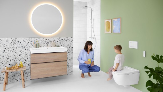 Donna e bambino in un bagno colorato con specchio Geberit Option e Geberit AquaClean Alba