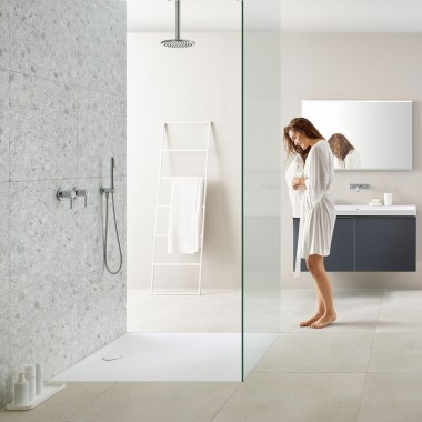 Donna in bagno con doccia walk-in e superficie doccia Geberit Olona