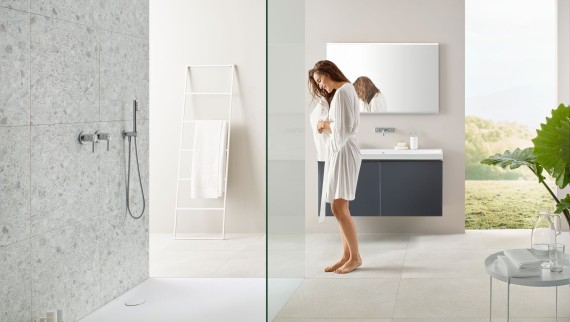 Donna in bagno con doccia walk-in e superficie doccia Geberit Olona