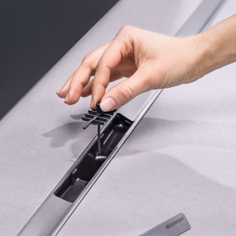 Hand platziert Kammeinsatz in den Abfluss Hand platziert Kammeinsatz in den Abfluss