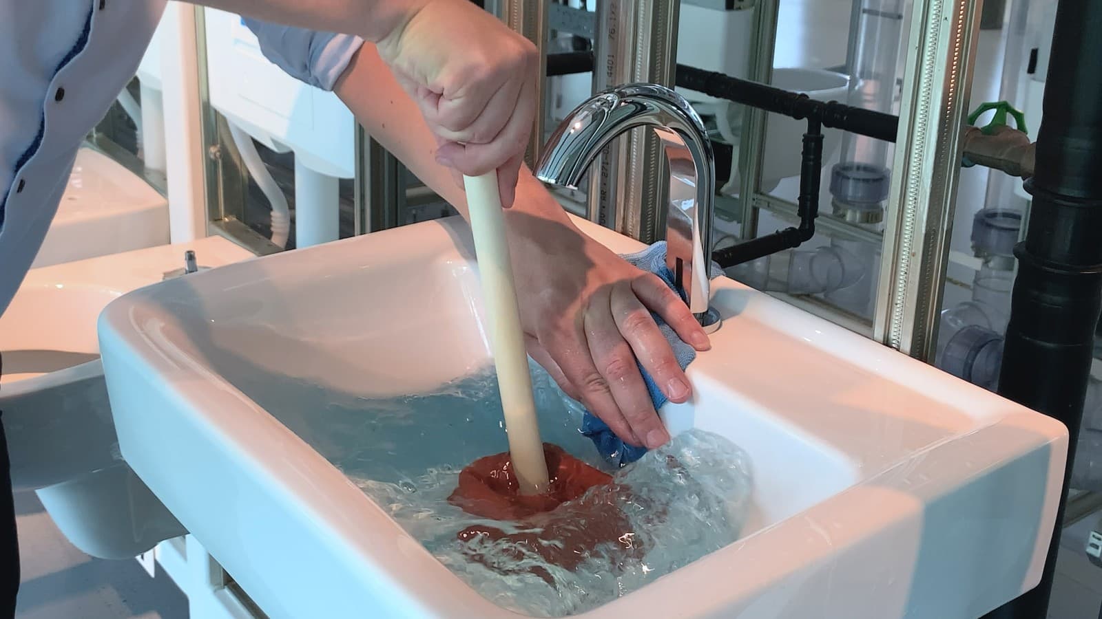 Mit der Hand und einem Lappen das Überlaufloch abdecken Mit der Hand und einem Lappen das Überlaufloch abdecken